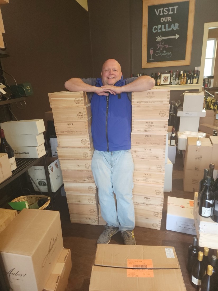 Gerry at the shop behind a wall of wine cases